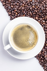 Coffee in a white cup on coffe beans and white background