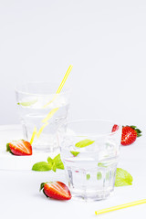 Two glasses of fresh lemonade and strawberries on a white table