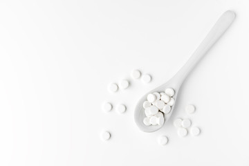 Pills on the spoon and scattered on the white surface