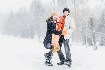 Cute family playing in the park in winter