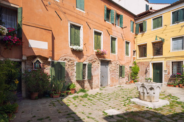 Fototapeta na wymiar Small, cozy courtyard with colorful cottage / Venice in Italy / The small yard with bright walls of houses