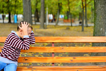 The young guy sits on a bench in park