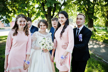 Wedding couple posing and having fun with bridesmaids and groomsmen in the park on a sunny day.
