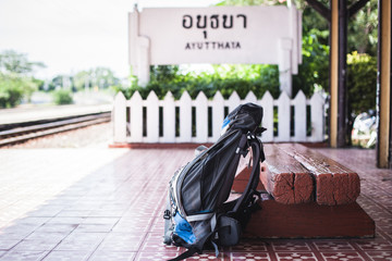 Blue Travel backpack put recline wooden bench and big wording Ayutthaya  train station.