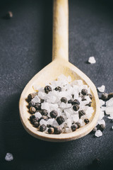 salt and pepper on a wooden spoon