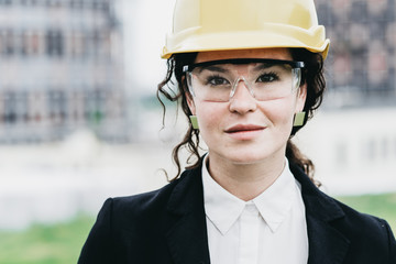 Close up portrait of beautiful girl in a yellow protective helmet and protective glasses, an architectural concept