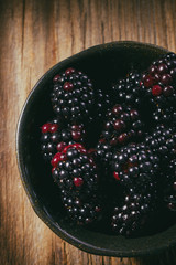 Blackberries in a bowl on a wooden table, top view
