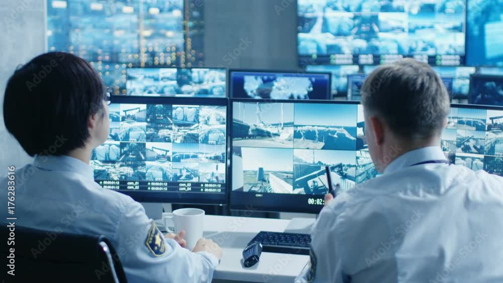 Aufkleber in the security control room two officers monitoring multiple screens for suspicious activities, the