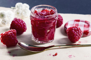 Mini jar of raspberrry marmelade and fresh fruits on a white napkin