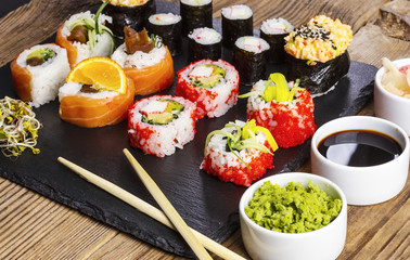 various kinds of sushi, soy sauce, wasabi and ginger on a wooden table