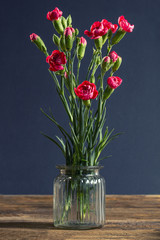 Pink carnations in glass vase on wooden table