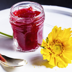 Raspberry jam and yellow flower on white