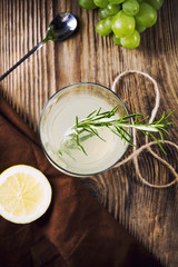 Gin tonic coctail with rosemary and lemon on wooden kitchen table, view from top