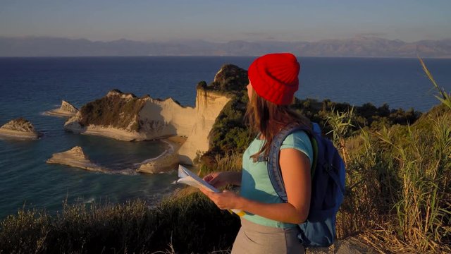 Woman with a backpack and map goes to the Cape Drastis at Corfu island in Greece
