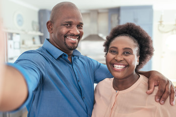 Smiling African couple taking a selfie together at home