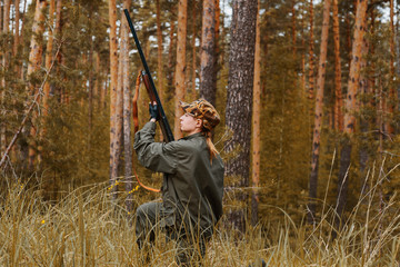 Woman hunter in the woods. Autumn hunting season. Outdoor sports.