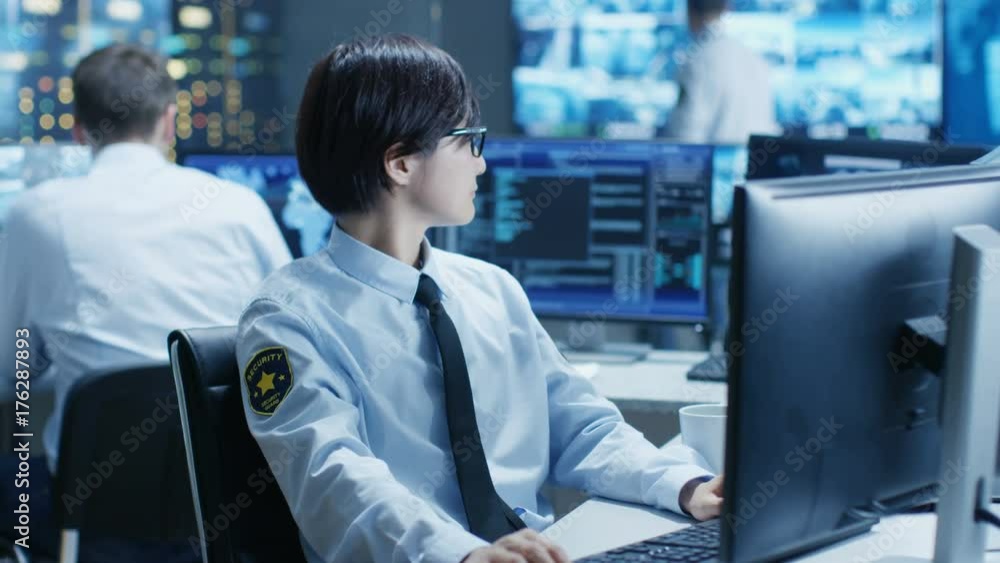Poster in the security command center officer at his workstation monitors multiple screens for unlawful inf