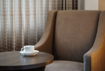 white coffee cup on the table by a sofa couch in hotel room