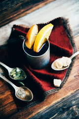 Mulled wine in rustic mug with spices and ingredients on wooden background. Top view, flat lay. Retro toned photo. Copy space for your text.
