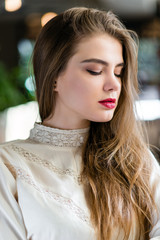 Portrait of beautiful young girl with professional makeup and hairstyle in restaurant.