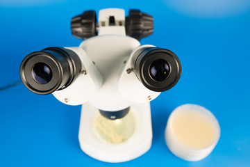 Scientific microscope and petri dishes for scientific research on blue background
