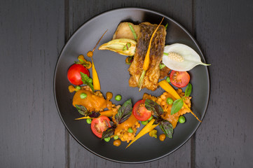 Dish from fried fish with lentils, green peas, apricot sauce, baby carrots and cherry tomatoes....