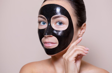 a black mask to the face of a beautiful woman. Spa treatments and care of the cats in the beauty salon.