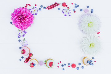 Frame of flowers and berries and whoopie pies. Top view.