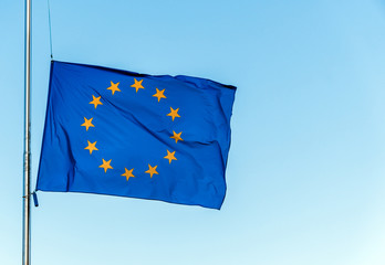 European Union flag on blue sky background, close up.