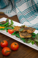 Fried fish with pea pods and cherry tomatoes.. Wooden background. Top view. Close-up