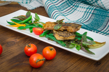 Fried fish with pea pods and cherry tomatoes.. Wooden background. Top view. Close-up