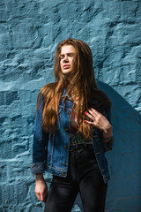 Portrait of a beautiful modern girl against blue brick background