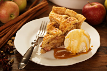 Piece of an apple pie with ice cream on a plate
