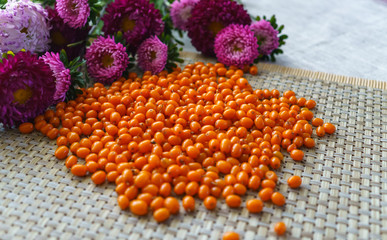a handful of scattered sea-buckthorn and a bouquet of lilac asters on the table.