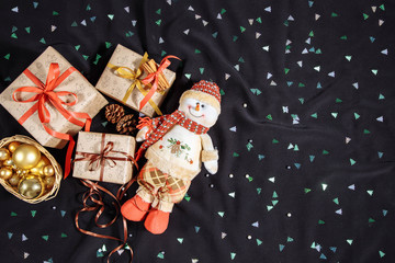 Christmas composition with copy space. Snowman, gifts boxes, Christmas decorations and cones on a dark background