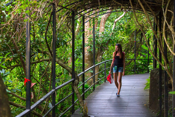The girl is walking along a bridge with a canopy in the jungle. Walk in the Yanoda National Park, Hainan, China.