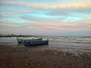 Fototapeta na wymiar Fishing boats at seaside under colorful sunset 