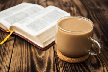 a cup of coffee and bible on wooden background
