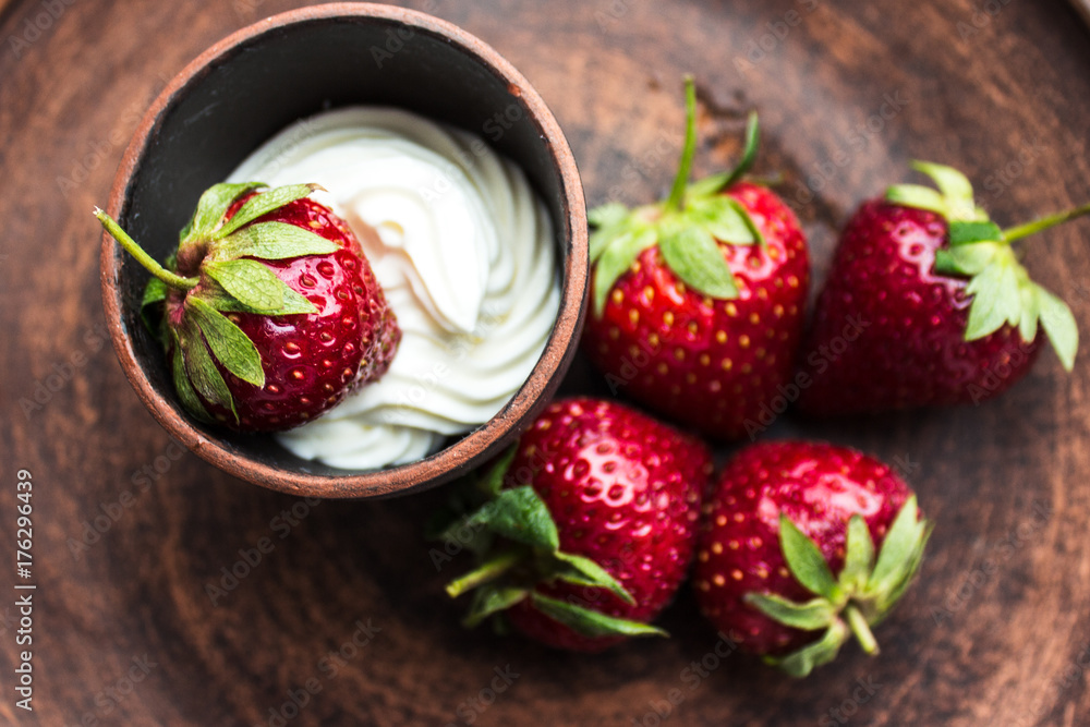 Wall mural fresh strawberry with whipping cream on a dark plate