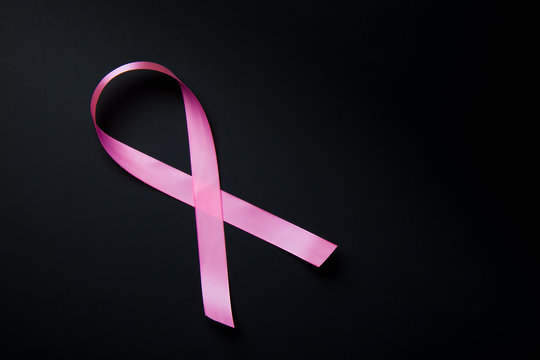 Breast Cancer concept. Pink ribbon symbol of breast cancer on black background.