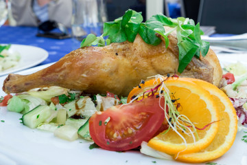 Whole grilled chicken served with fresh vegetables and a glass of wine in the restaurant of Szeged, Hungary
