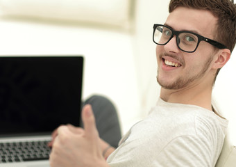modern young sitting in front of the open laptop and showing thumb up