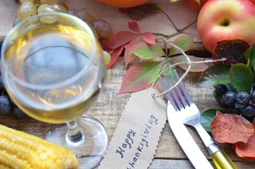 Autumn place setting. Thanksgiving dinner. Fall season fruit, pumpkins, plates, wine and candles. Thanksgiving dinner
