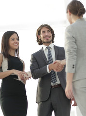 Businesspeople  shaking hands against room with large window loo