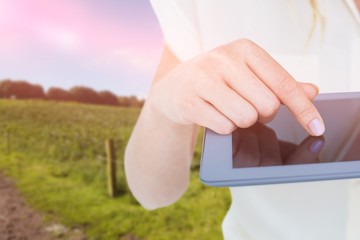 Composite image of woman using tablet pc against rural landscape