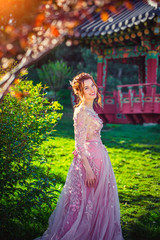 Obraz na płótnie Canvas Beautiful woman in pink dress. Background of Japanese architecture in garden. Spring garden. 