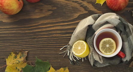 a cup of hot tea with a lemon wrapped in a scarf on a wooden table