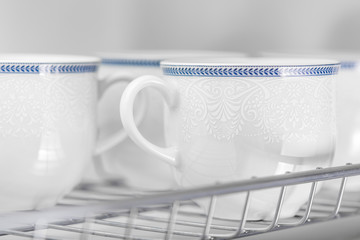 Set of clean white cups located on the shelf