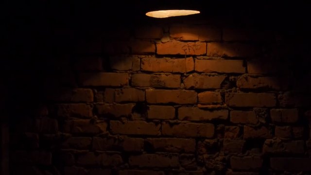 The old brick wall is lit by a flashlight