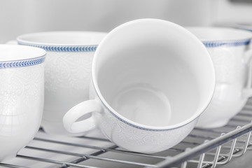 Set of clean white cups located on the shelf